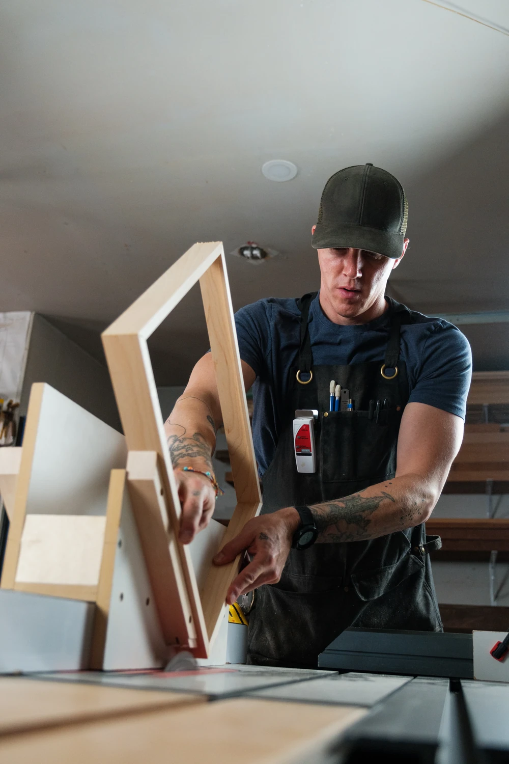 A craftsperson working on a wooden object at a workbench.
