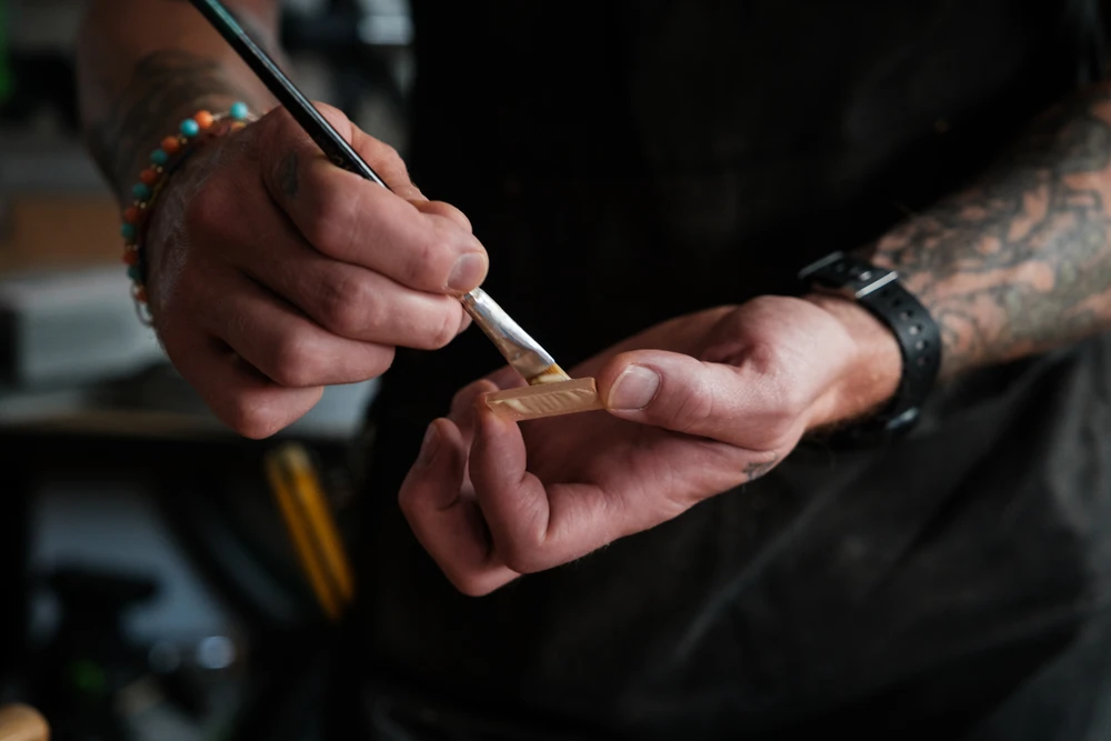Hands carefully applying glue to a wooden joint.