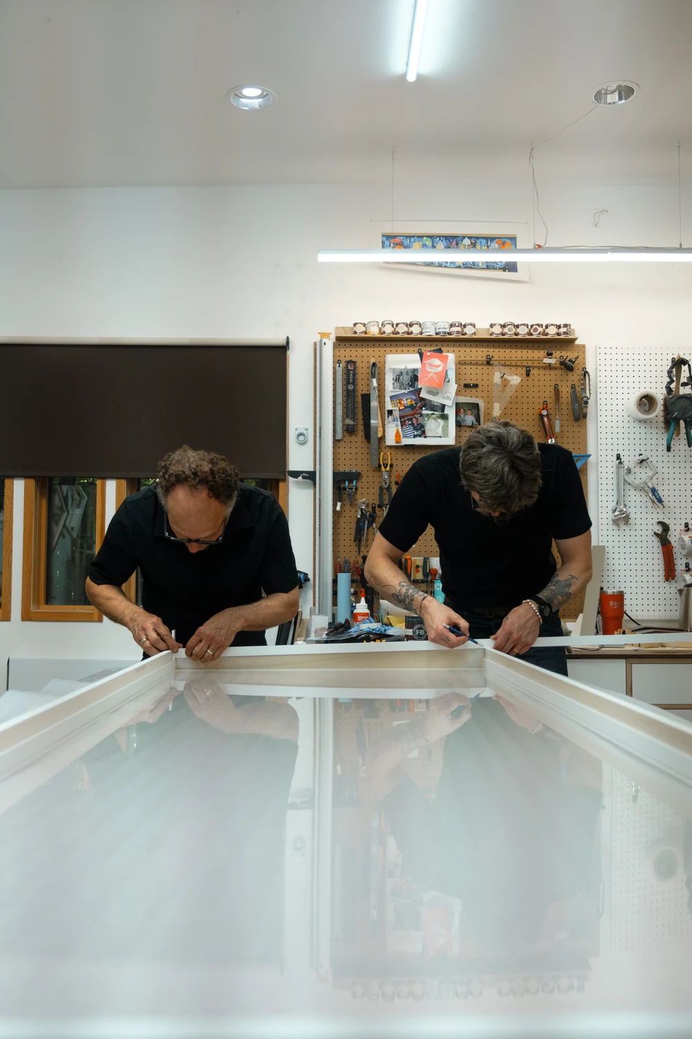 Two people working together across a large surface in a workshop.