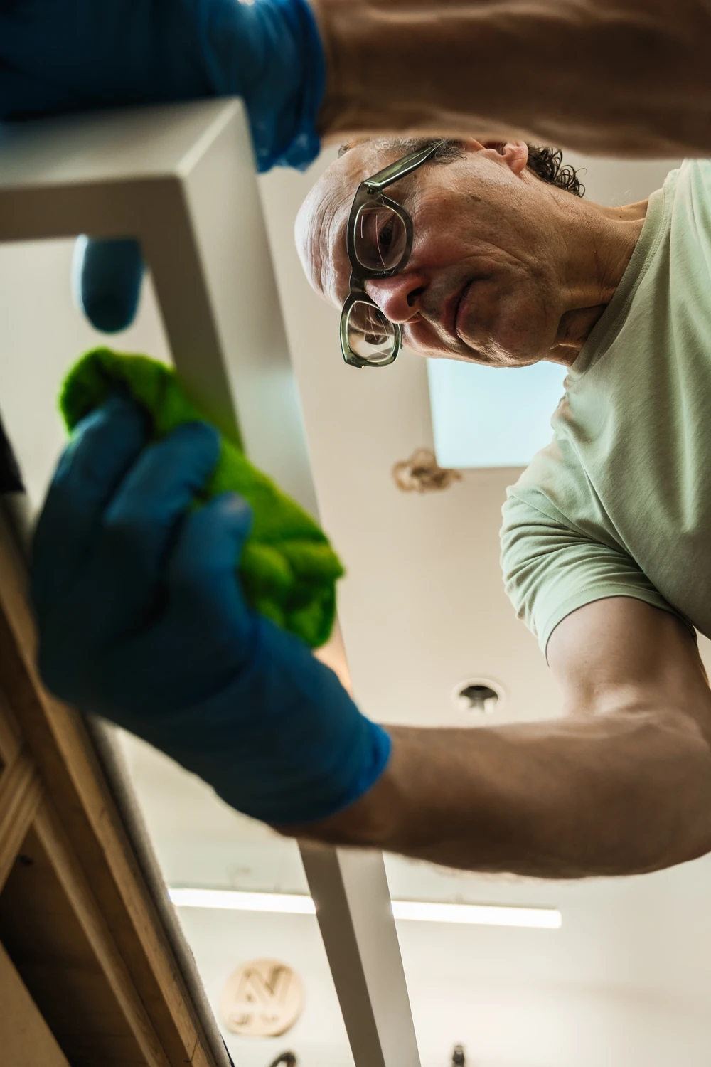 Wearing a blue glove makes a finishing adjustment, seen from below.