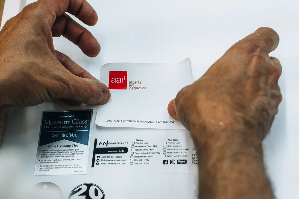 Hands working beside an Alberta Art Installation label.