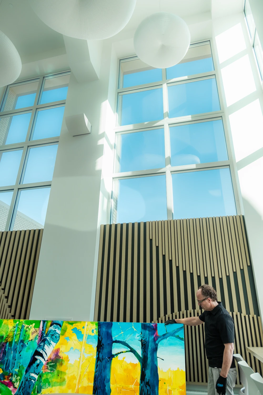 An installer beneath tall windows and sculpted ceiling forms in the Cross Cancer Institute