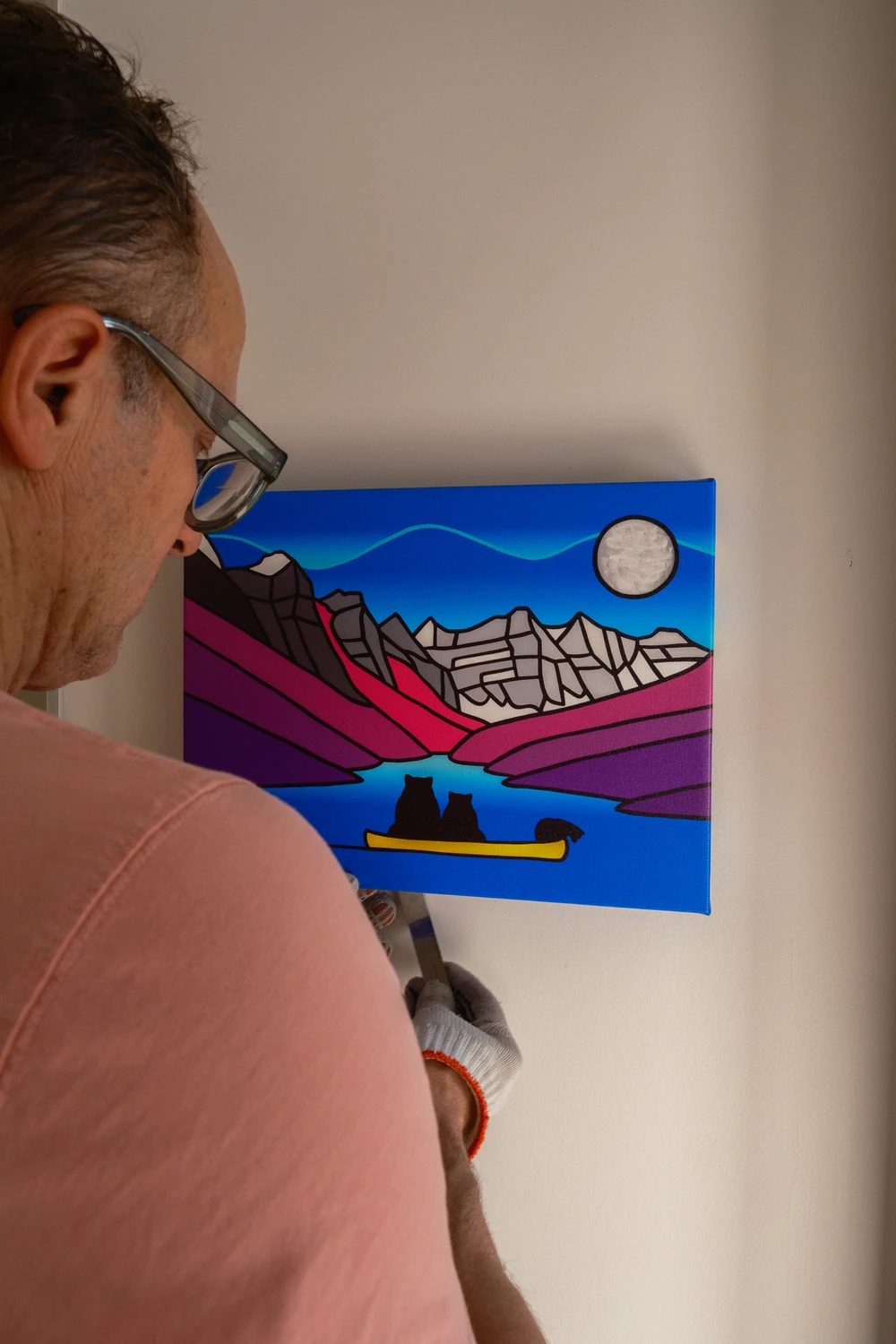 An installer using a tool beside a smaller artwork.