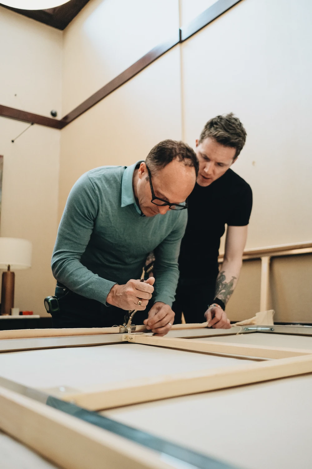 Two people concentrating on a frame in a workshop.