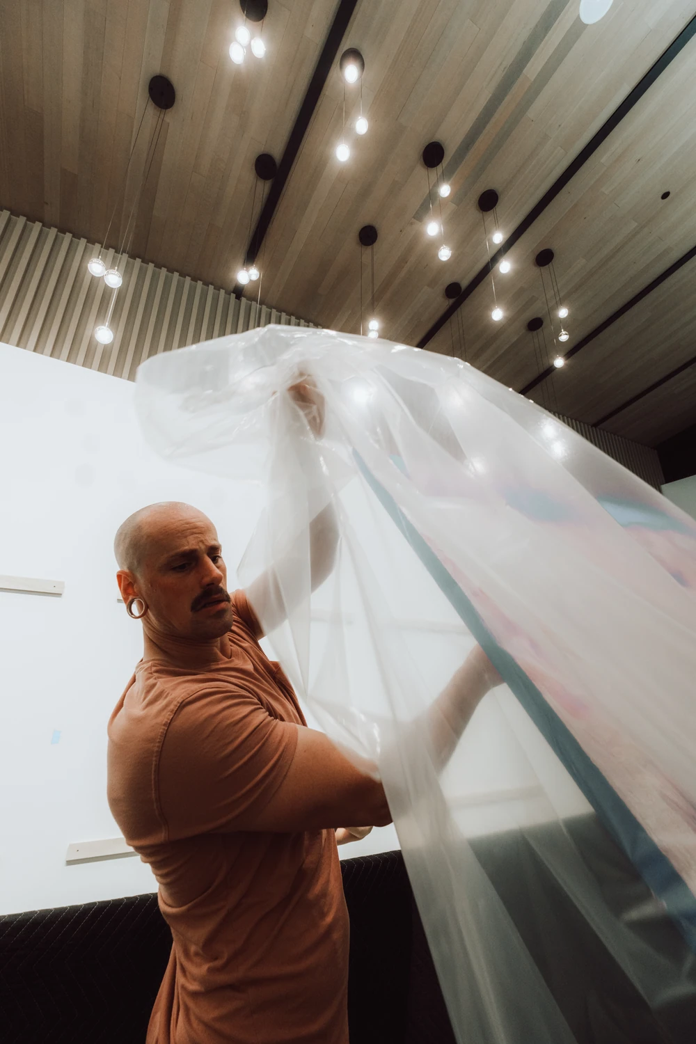 An installer handling a large artwork and its protective covering.