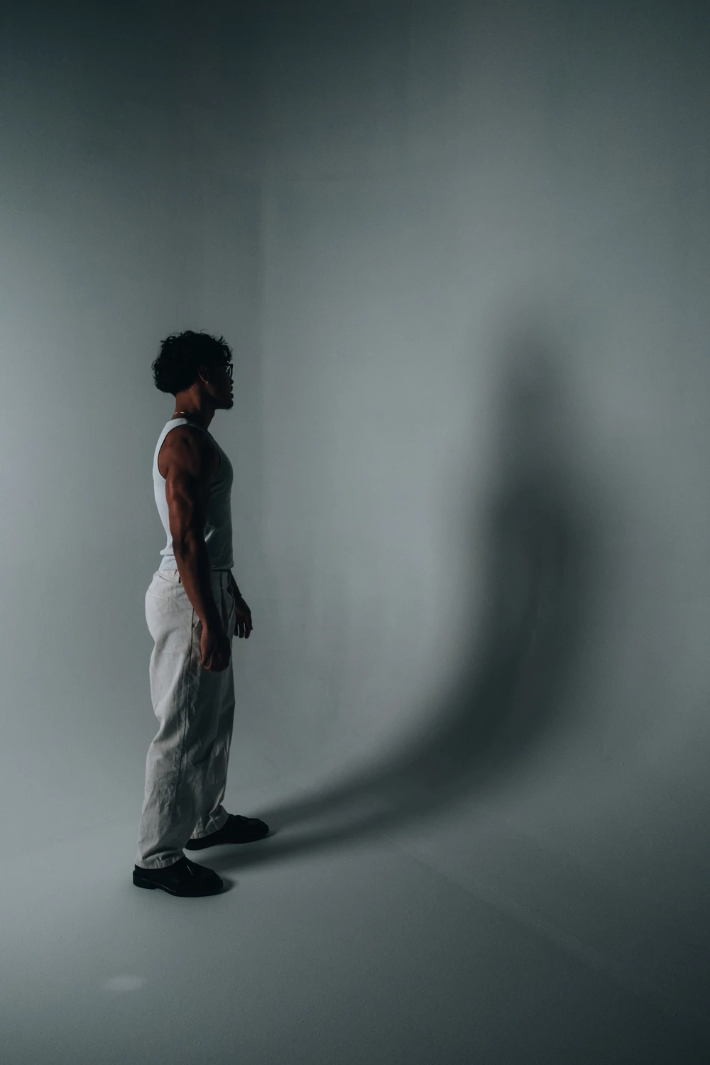 An artist in side profile casting a long shadow across a grey studio wall.