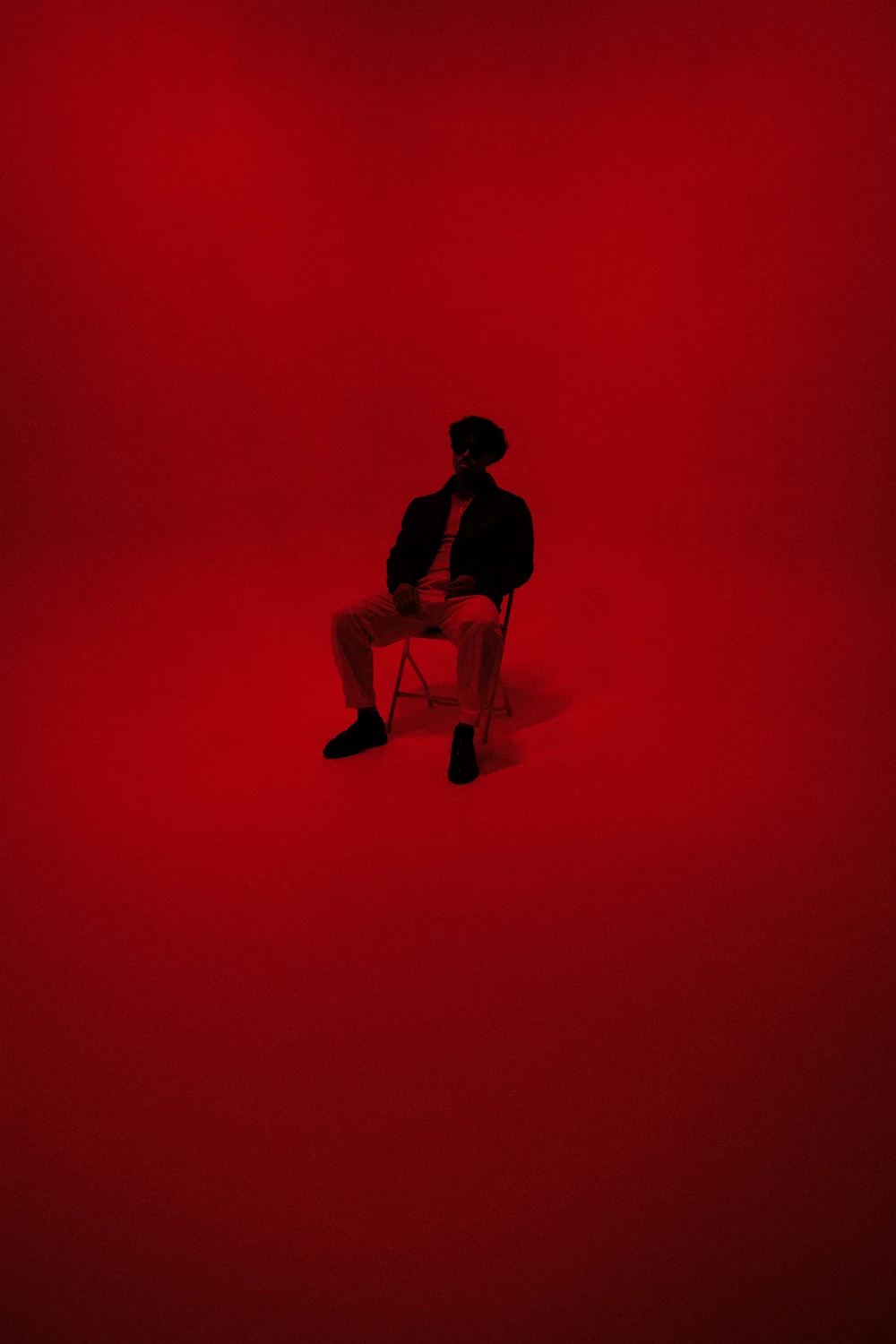 A seated artist under deep red studio lighting.
