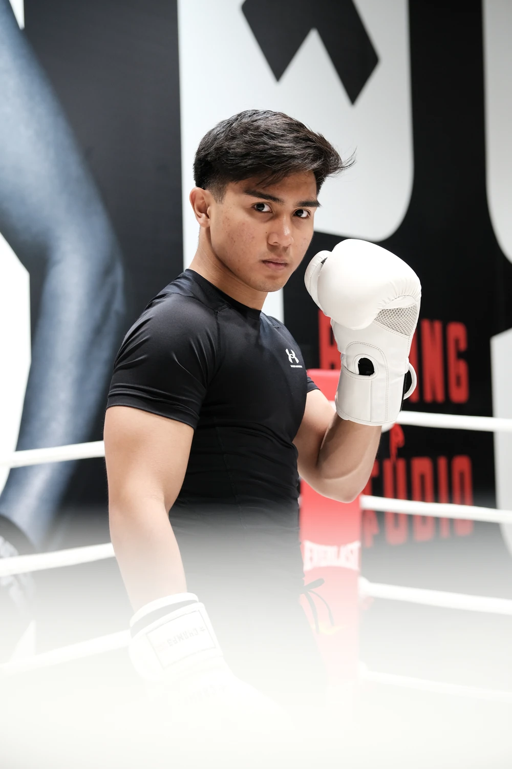 A boxer in guard position framed by ring ropes.