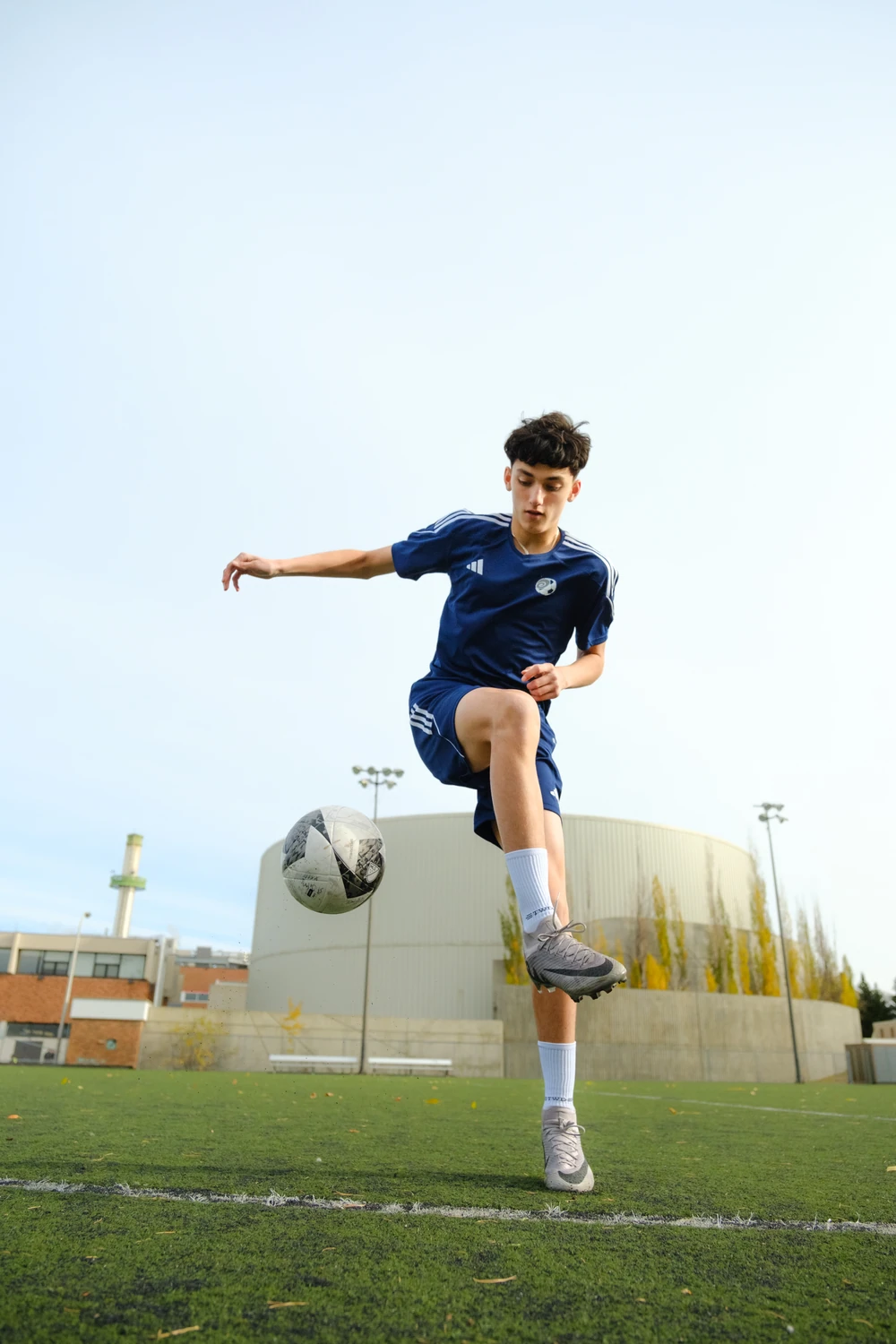 A football player with the ball suspended in the air, photographed from a low viewpoint.