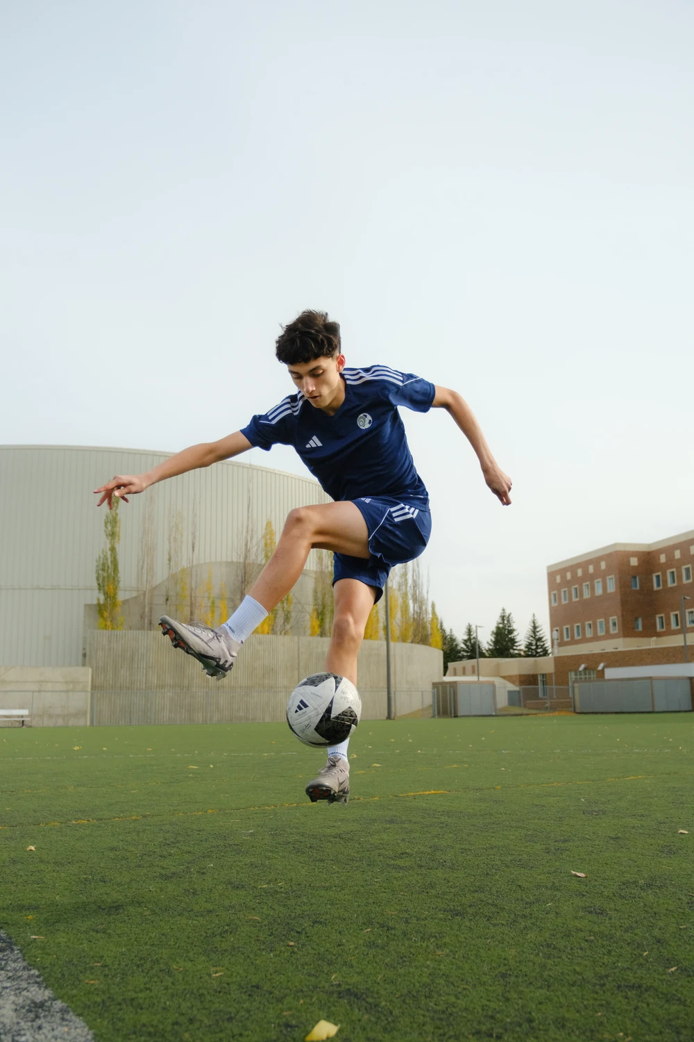 A football player airborne while moving a leg around the ball.