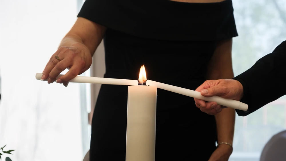 Hands lighting a candle during a wedding ceremony.