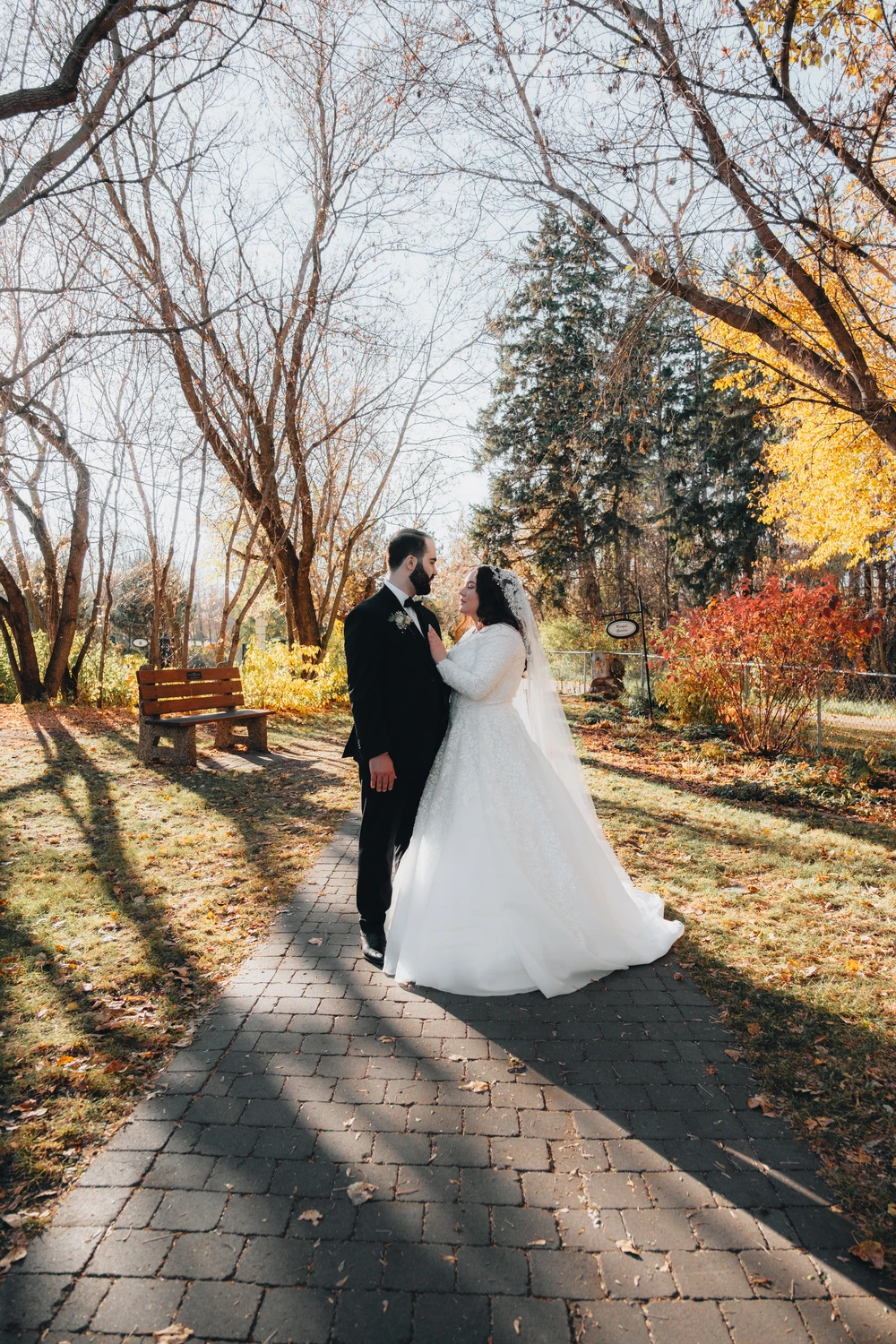 A wedding couple walking along an autumn path.