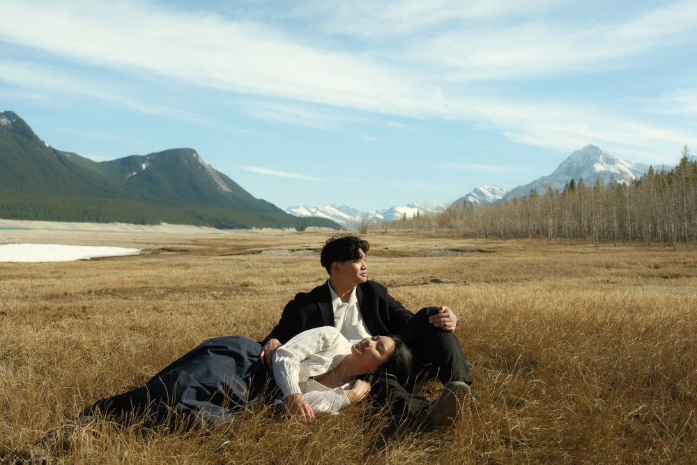 A couple reclining together in a mountain landscape.