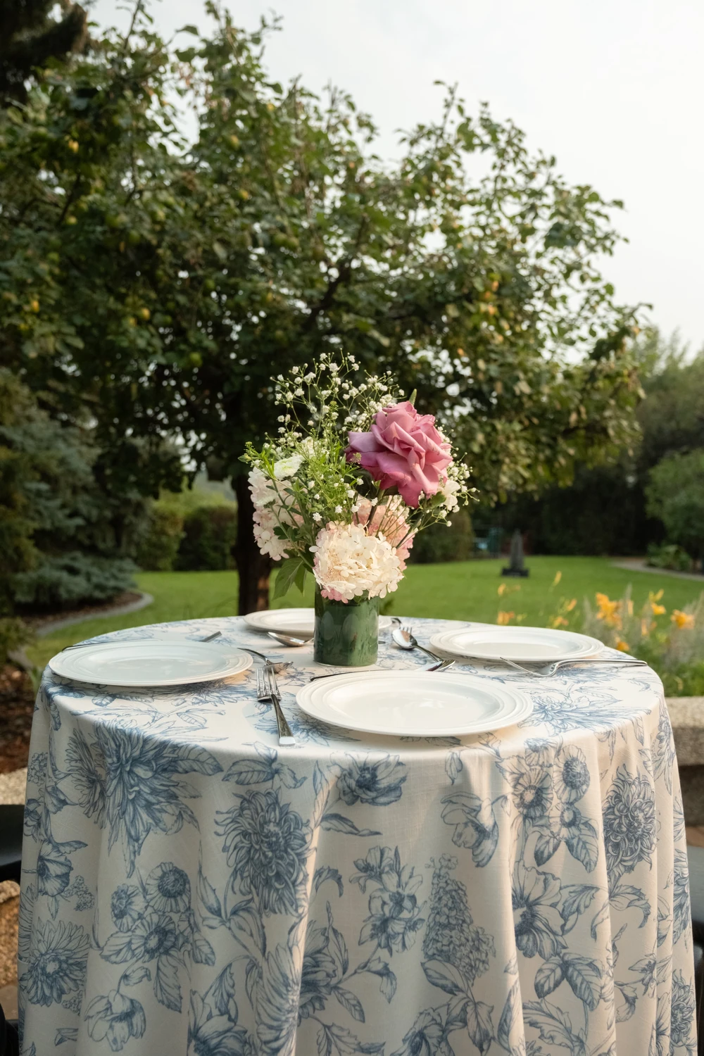 Flowers and place settings on a garden reception table.