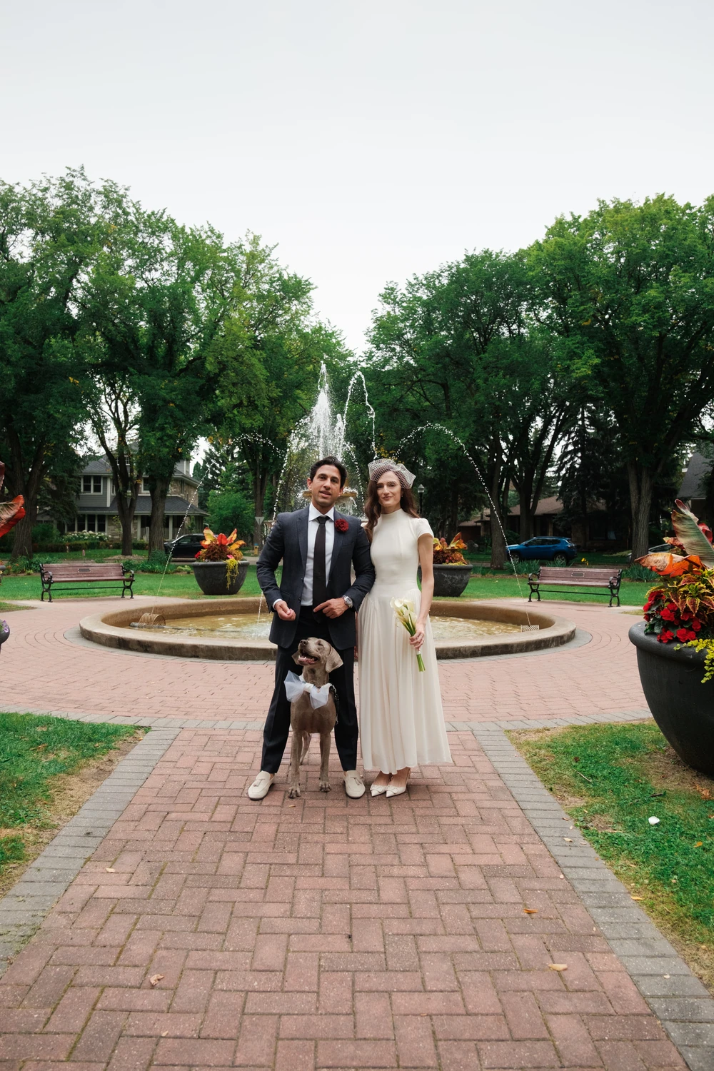 A wedding couple and their dog in a garden.