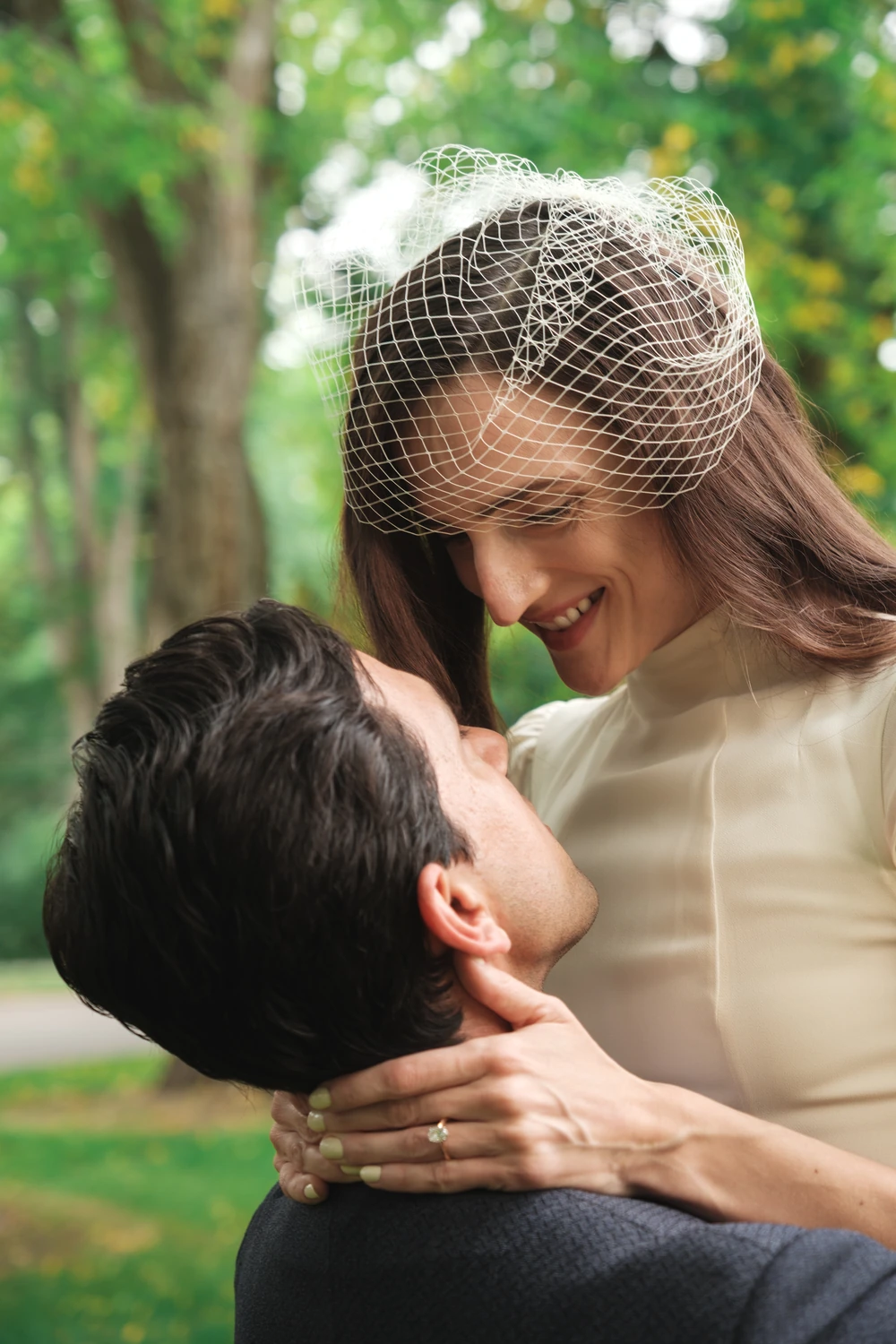 One partner lifting the other during a smiling wedding portrait.