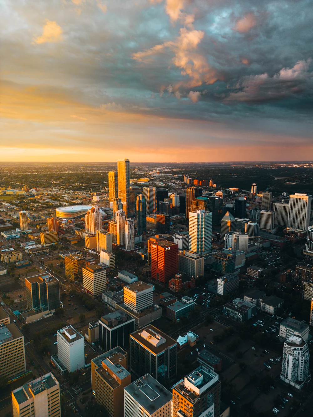 An aerial view of downtown Edmonton with warm evening light on the towers and clouds.