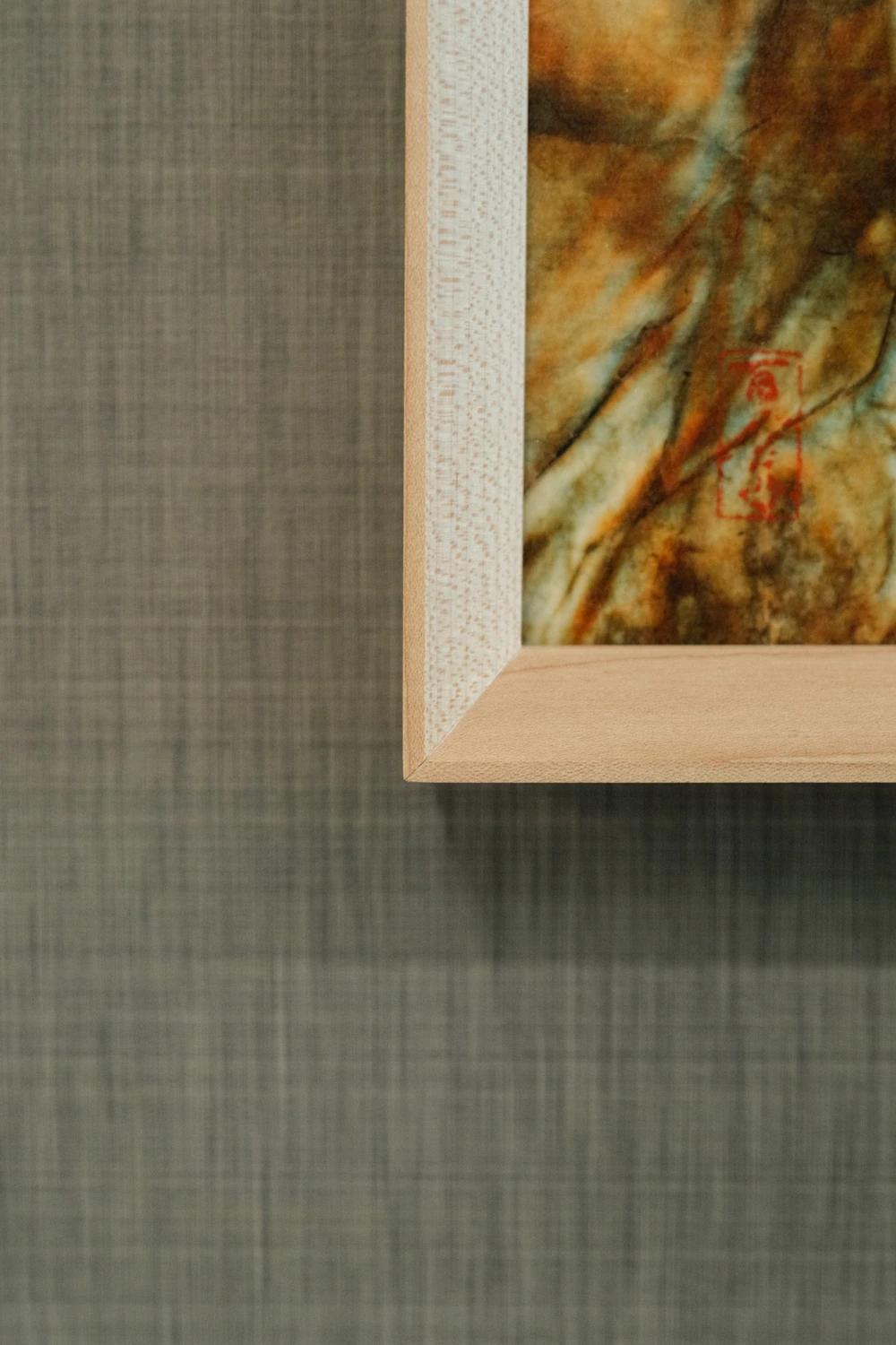A close view of a wooden frame corner, textured artwork and fabric-covered wall at NBC.