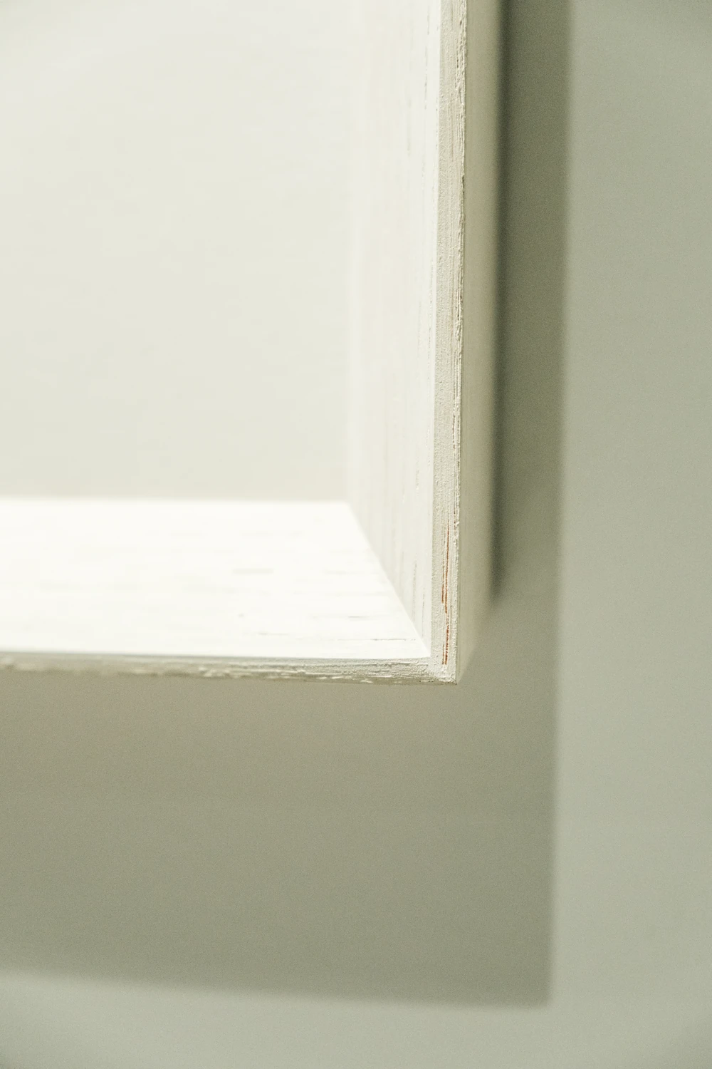 The lower corner of a white frame casting a soft rectangular shadow on a wall at NBC.