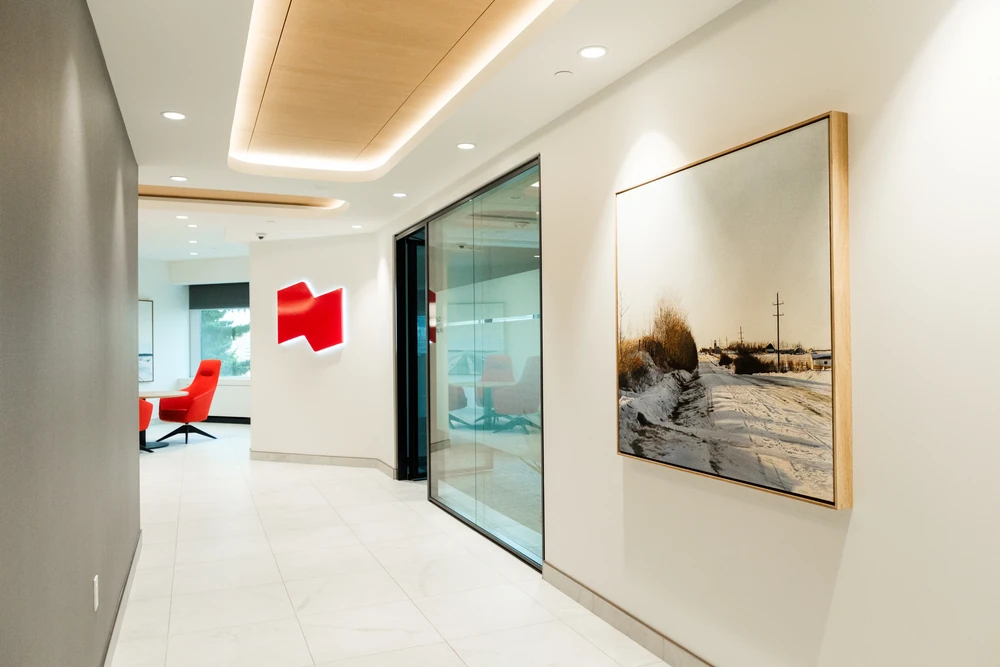 A bright NBC corridor with the red NBC logo, glass doors and a framed winter landscape artwork.