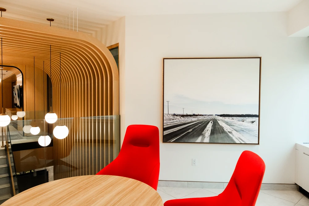 Red chairs, curved wooden slats and a framed winter-road artwork in a bright NBC interior.