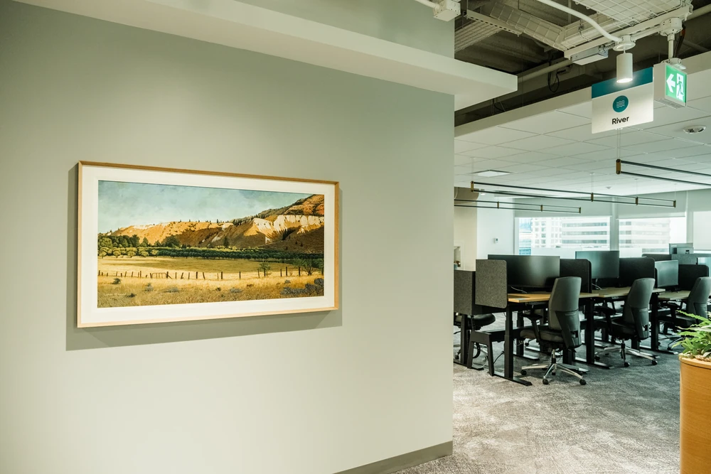 A framed landscape artwork beside an open office area at NBC.