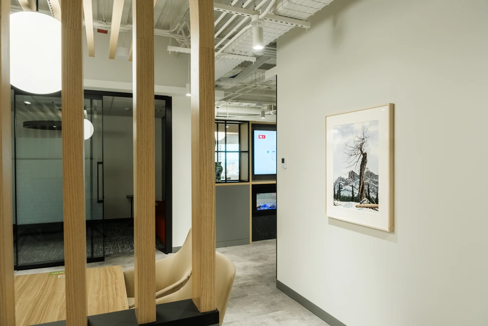 Curving wooden slats, pendant lights and a framed tree artwork in an NBC interior.