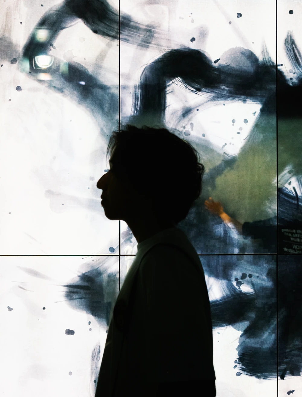 A person in side-profile silhouette against a large abstract black-and-white display.