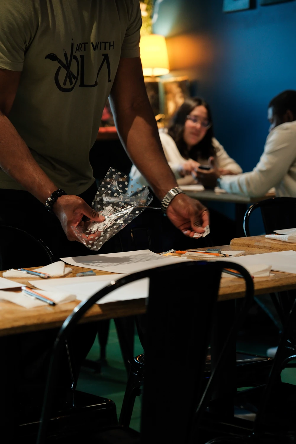 Hands preparing art materials on a table during the workshop.