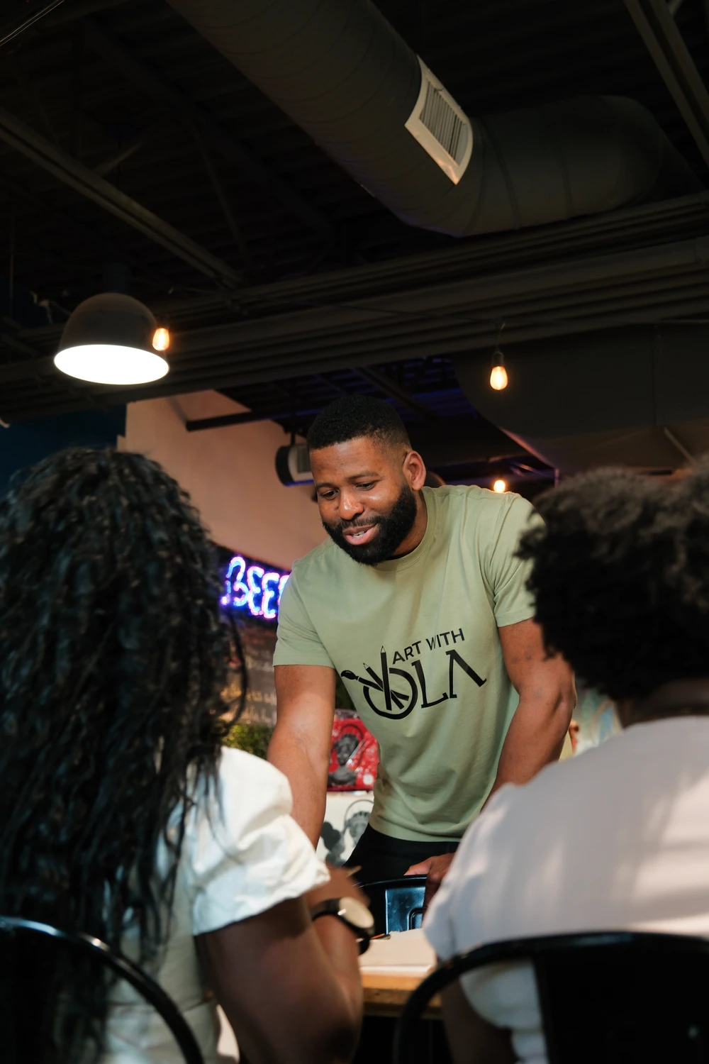 Ola smiling while talking with participants around a table.