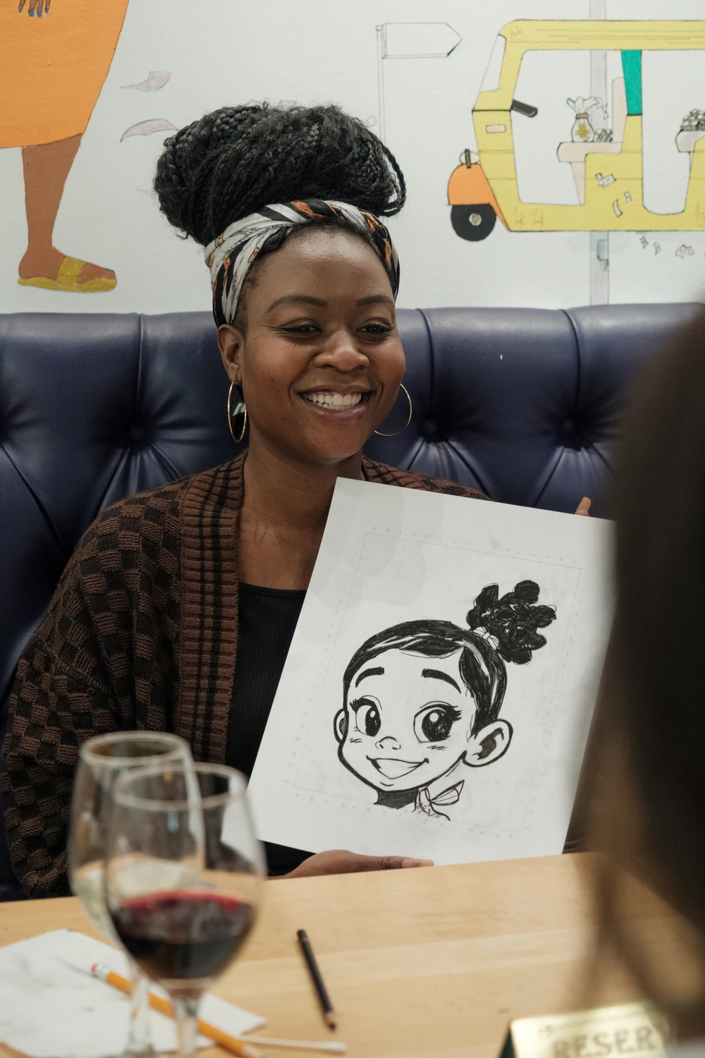 A smiling workshop participant holding up her completed drawing at an Art with Ola session.