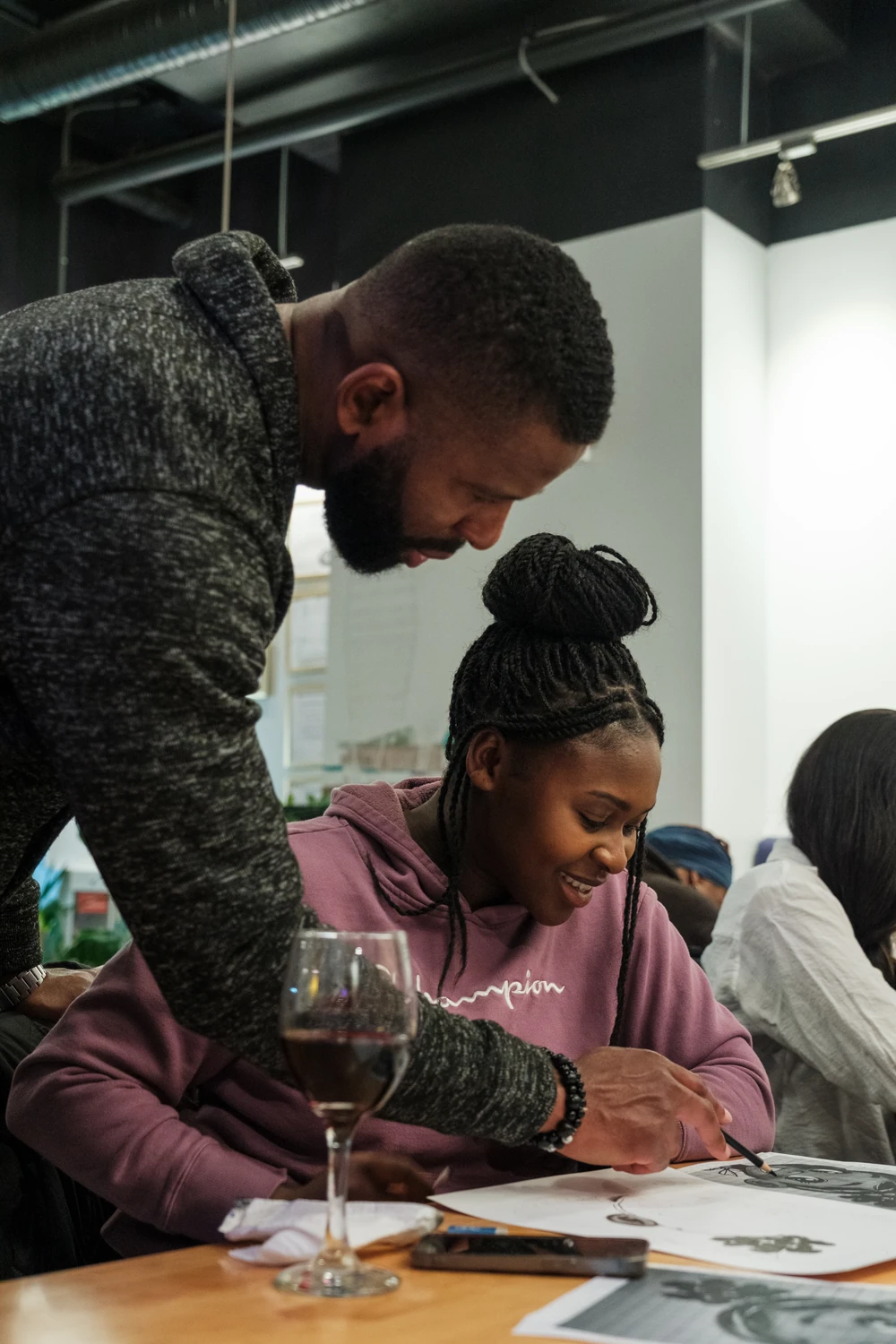 An instructor guiding a participant as she works on a drawing.